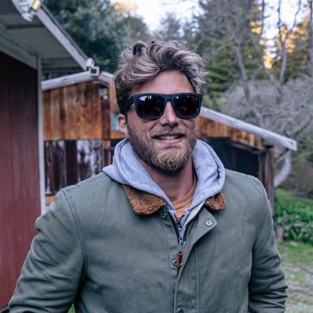 Man wearing Discord sunglasses with a jacket in the outdoors. 